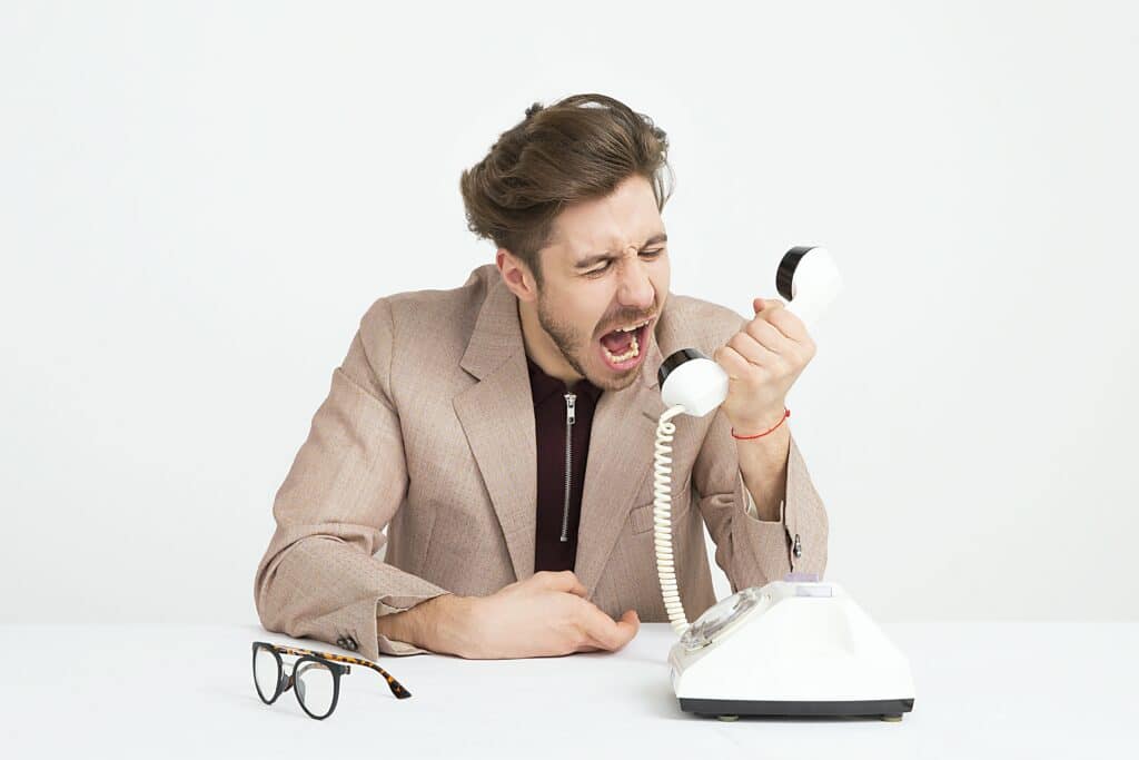 Un homme criant dans un téléphone, symbole des tensions causées par une communication inefficace